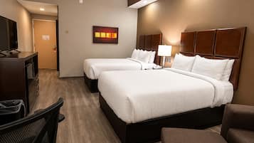 Habitación de hotel con dos camas, un escritorio, una silla y un televisor.