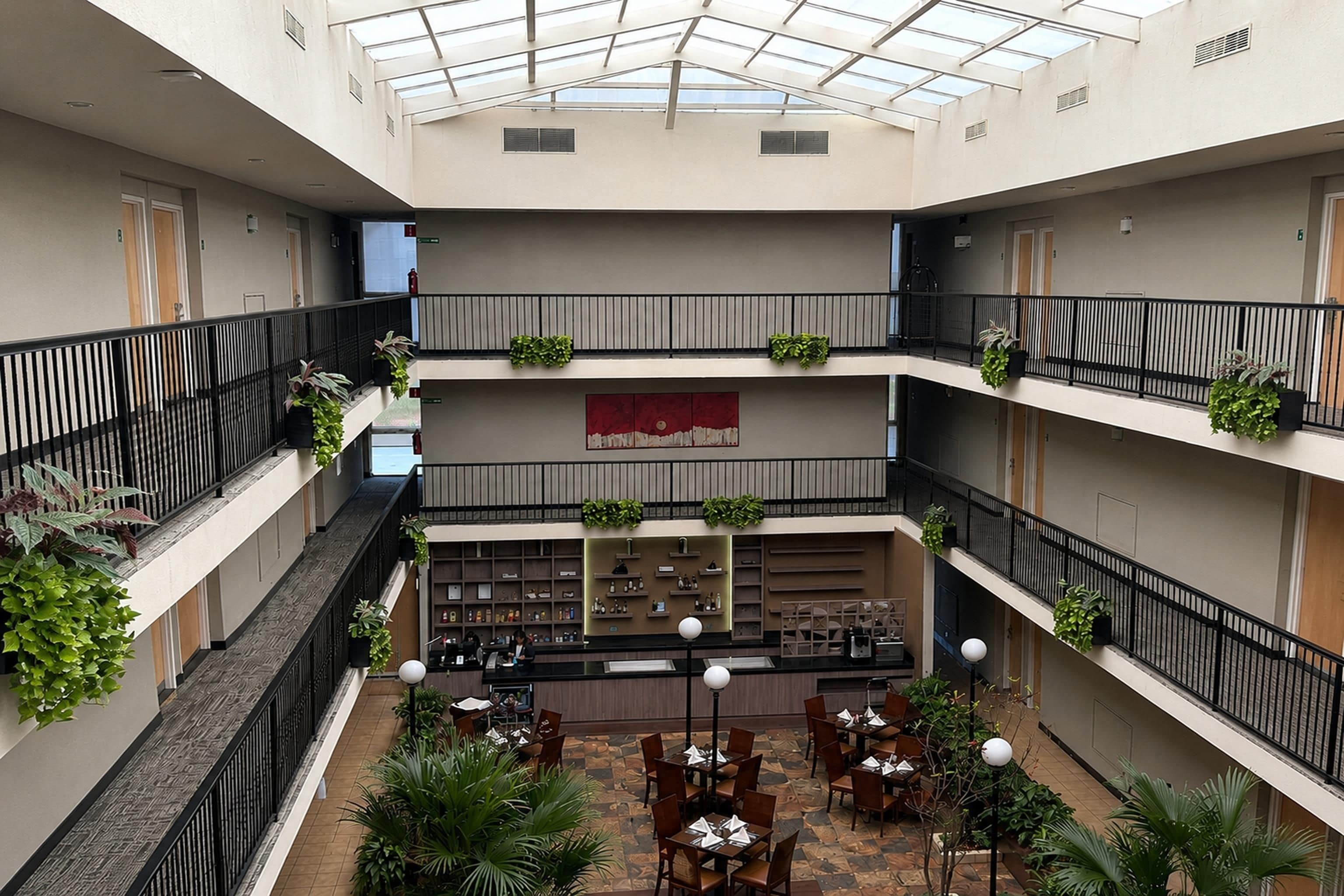 Un atrium à plusieurs niveaux, doté d’un toit en verre, d’un espace de détente intérieur et de plantes.