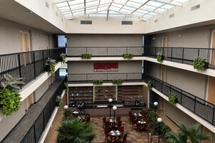 A multi-level atrium with a glass ceiling, indoor seating area, and greenery.