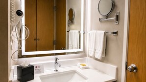 A bathroom with a white sink, a mirror, a towel rack, and a wooden door. - Best Western Plus Monterrey Airport (Apodaca)