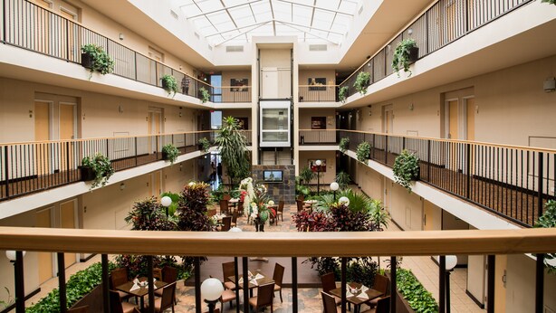 Un atrio de varios niveles con techo de vidrio, varios balcones y plantas de interior.