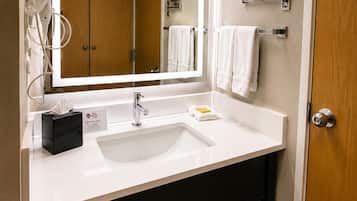 A modern bathroom with a white sink, a mirror, a towel rack, and a wooden door.