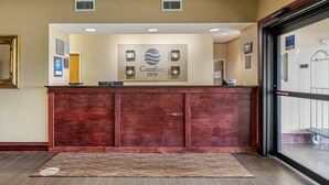 Un comptoir d’accueil avec une enseigne indiquant « Comfort Inn » et un espace d’accueil doté d’un comptoir en bois et d’un tapis à motifs.