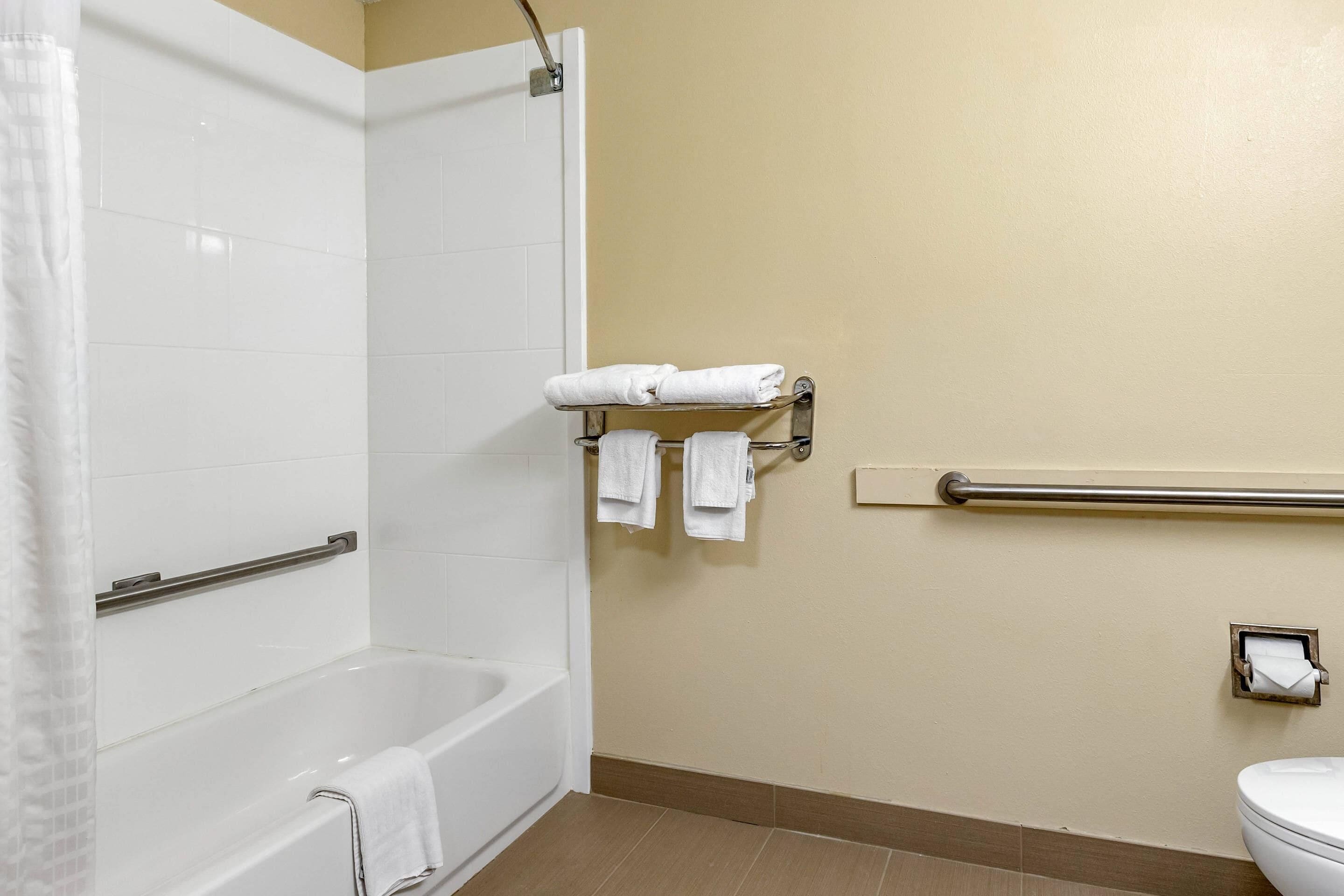 Et badeværelse med badekar, toilet og et håndklædestativ med håndklæder.