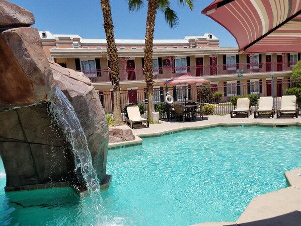 Una piscina techada, una piscina al aire libre, sombrillas