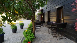 An outdoor seating area with tables and chairs, surrounded by potted plants and a cobblestone path. - Yusufpasa Konagi - Special Class (Istanbul)