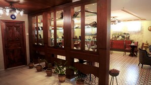 A lobby with a wooden reception desk, glass display cabinets, potted plants, and a patterned floor. - Yusufpasa Konagi - Special Class (Istanbul)
