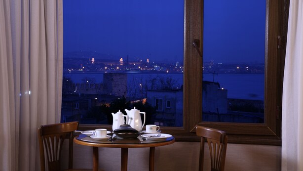 A dining table with white tableware and a view of a cityscape at night through a window. - Yusufpasa Konagi - Special Class (Istanbul)