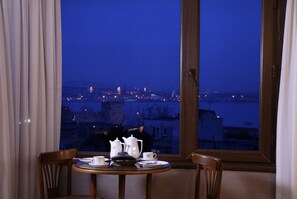 A dining table with white tableware and a view of a cityscape at night through a window. - Yusufpasa Konagi - Special Class (Istanbul)