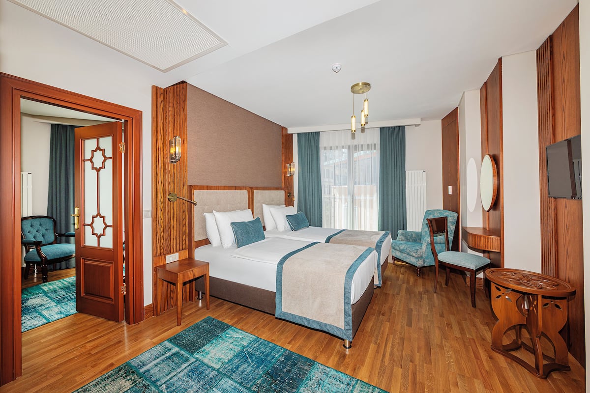 A hotel room with a large bed, two bedside tables, a desk, a chair, and a TV.
