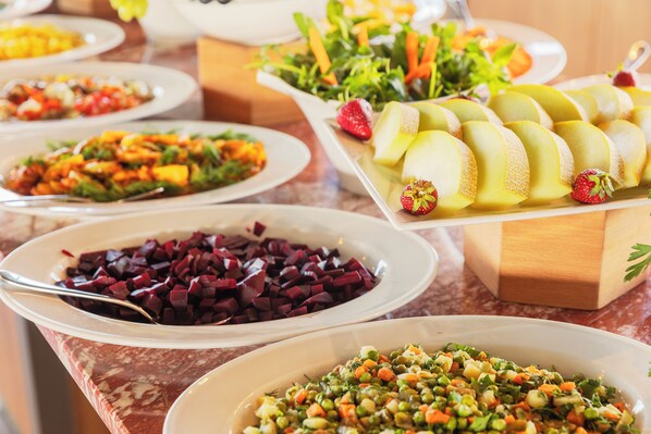 A buffet with various dishes including beets, a fruit platter, and a vegetable salad. - Triton Hotel (Istanbul)