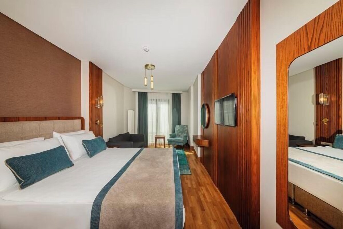 Une chambre d’hôtel avec un lit, une table de chevet, un miroir et une vue sur le couloir.