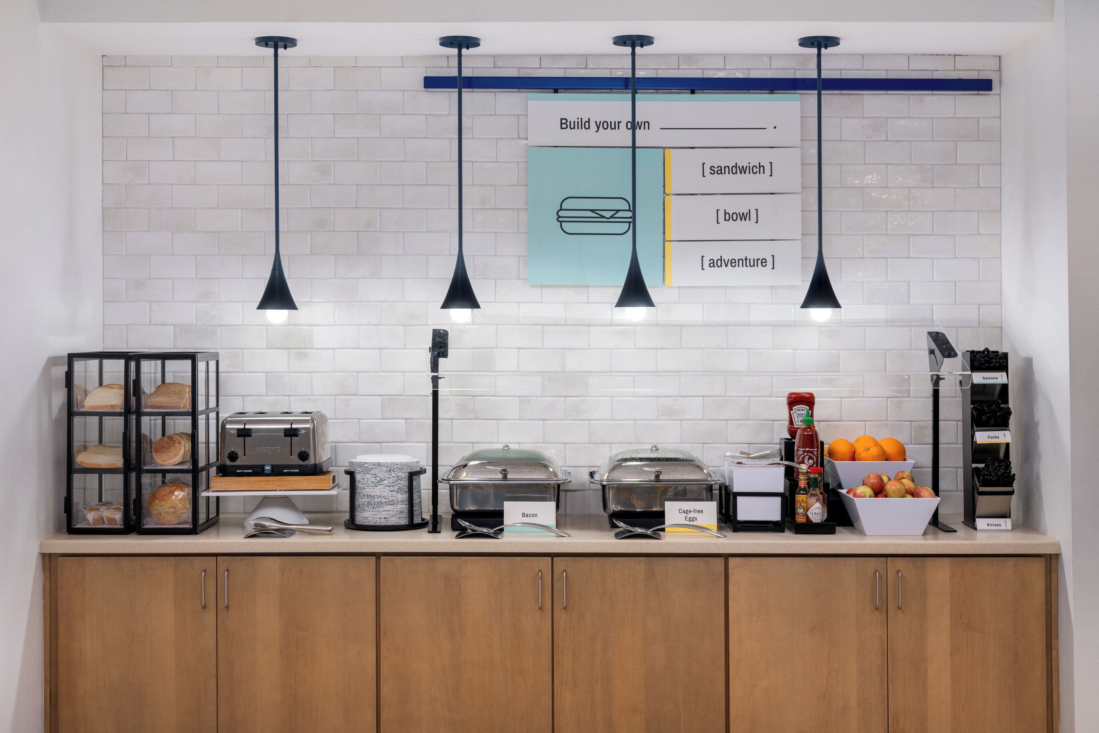 A breakfast bar with bread, toaster, and labeled containers for bacon and egg-free options.
