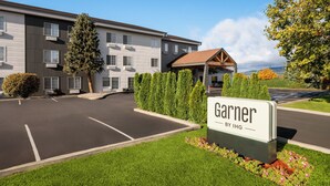 Un hotel en Garner con estacionamiento, un área exterior techada y jardines bien cuidados.