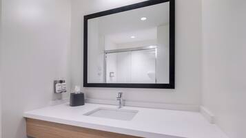 A modern bathroom with a white sink, a black-framed mirror, and a wooden vanity.