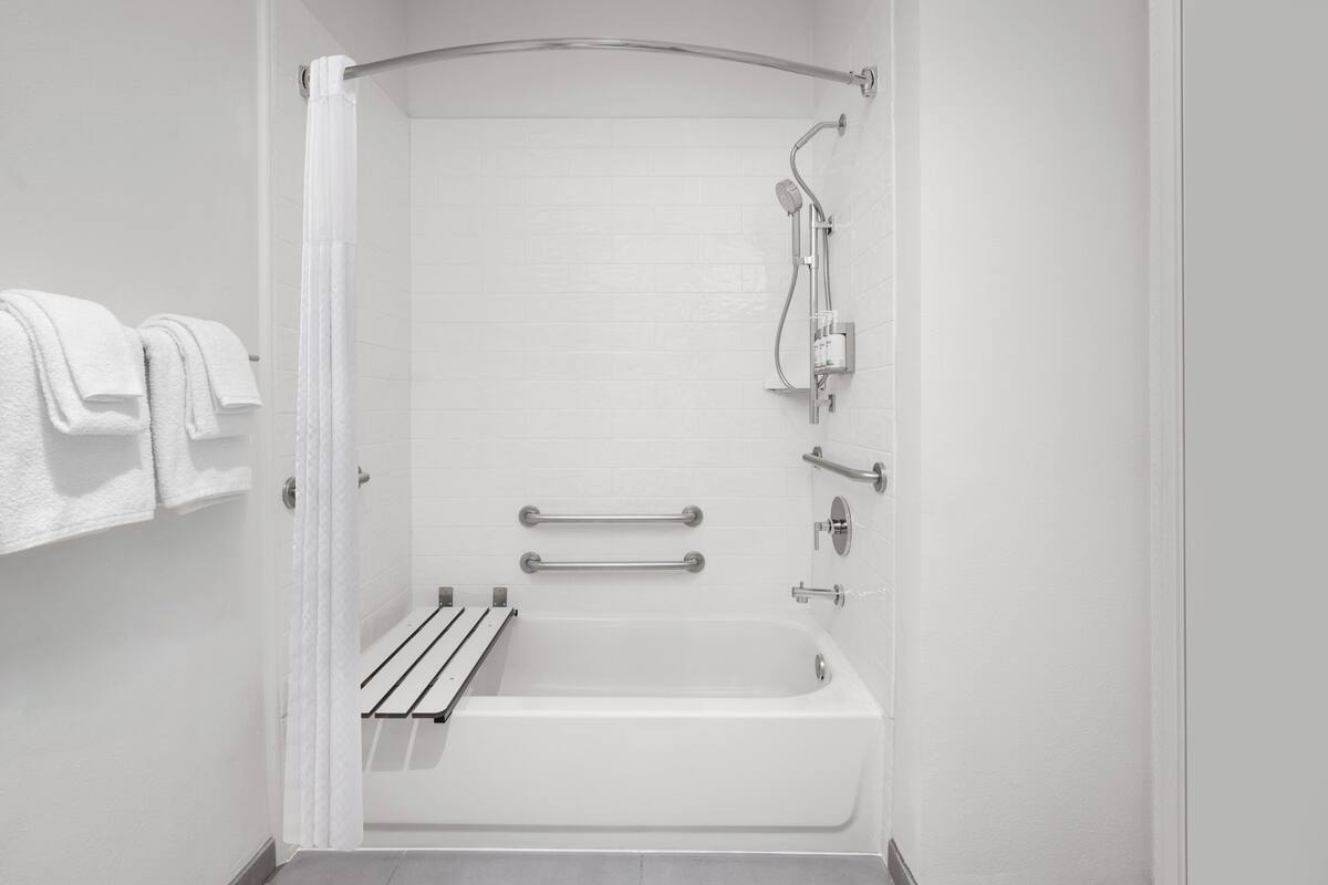 Un baño moderno con bañera, ducha y barras de apoyo.