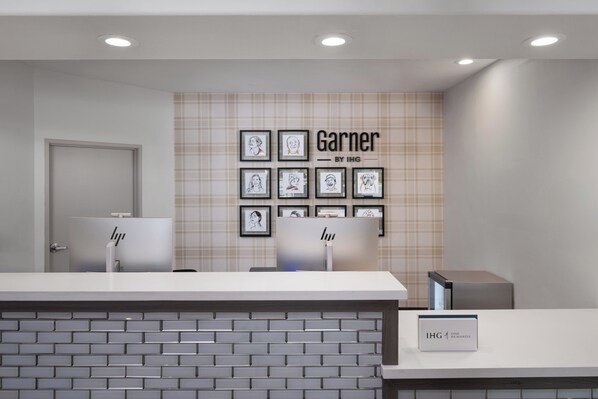 A reception area with a check-in counter, a wall with framed portraits, and a sign for IHG Rewards.
