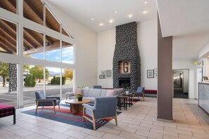 Un lobby amplio con chimenea de piedra, asientos cómodos y ventanas grandes que ofrecen vistas al exterior.