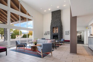 A spacious lobby with a stone fireplace, comfortable seating, and large windows offering a view of the outdoors.
