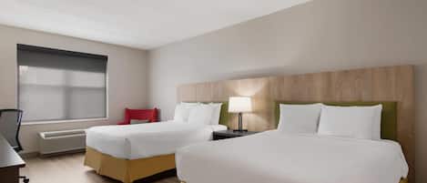 Habitación de hotel con dos camas, un escritorio, una silla y una ventana con persianas.