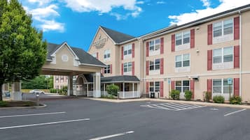 Classic hotel building with a covered entrance and parking area.