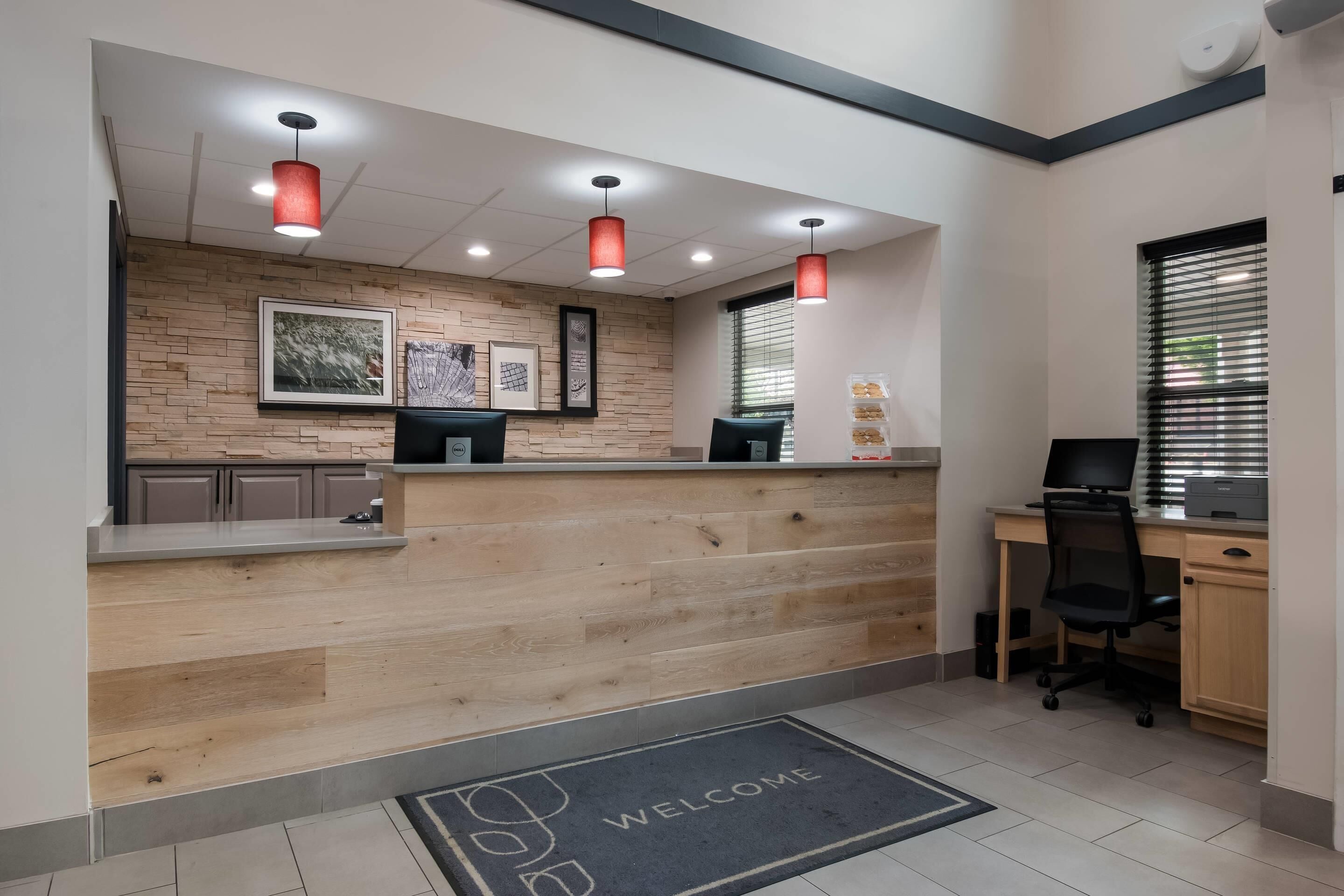 A reception area with a wooden counter, a computer, and a desk with a chair.