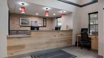A reception area with a wooden counter, a computer, and a desk with a chair.
