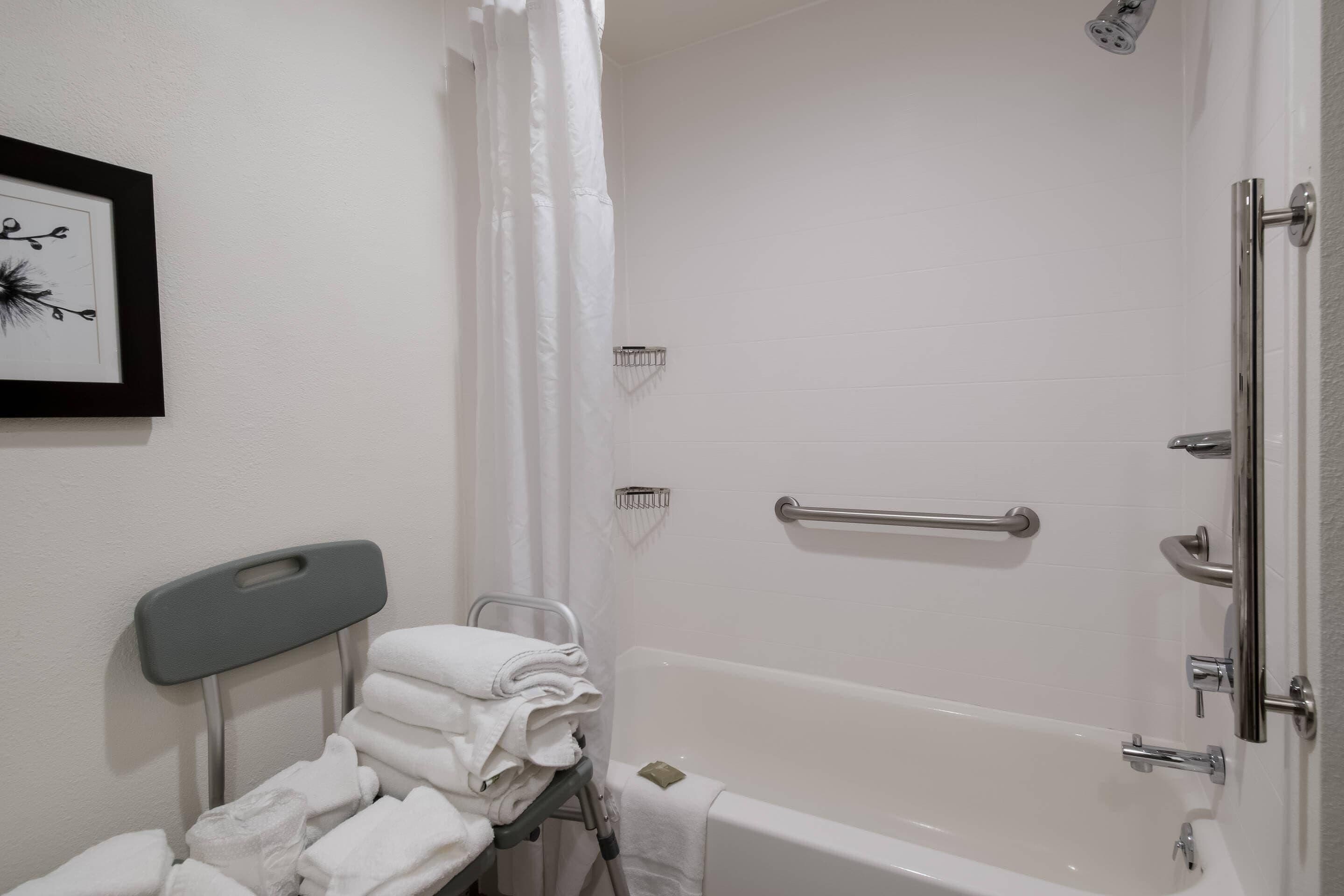 Ein Badezimmer mit Badewanne, Dusche, Handtuchhalter und einem gerahmten Bild an der Wand.