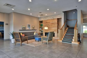 A spacious living area with a sofa, two chairs, a coffee table, and a staircase leading to an upper level.