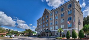 A multi-story hotel with a prominent 'Country Inn & Suites' sign, a parking lot, and a landscaped entrance area with palm trees.