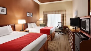 Une chambre d’hôtel avec deux lits, un bureau avec une télévision, une chaise et une fenêtre avec des rideaux.