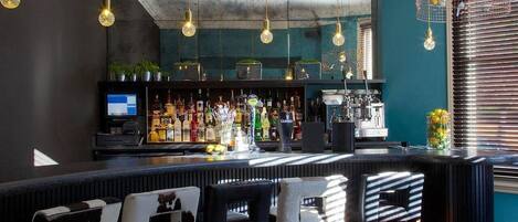 A bar area with a counter, bar stools, and hanging light fixtures.