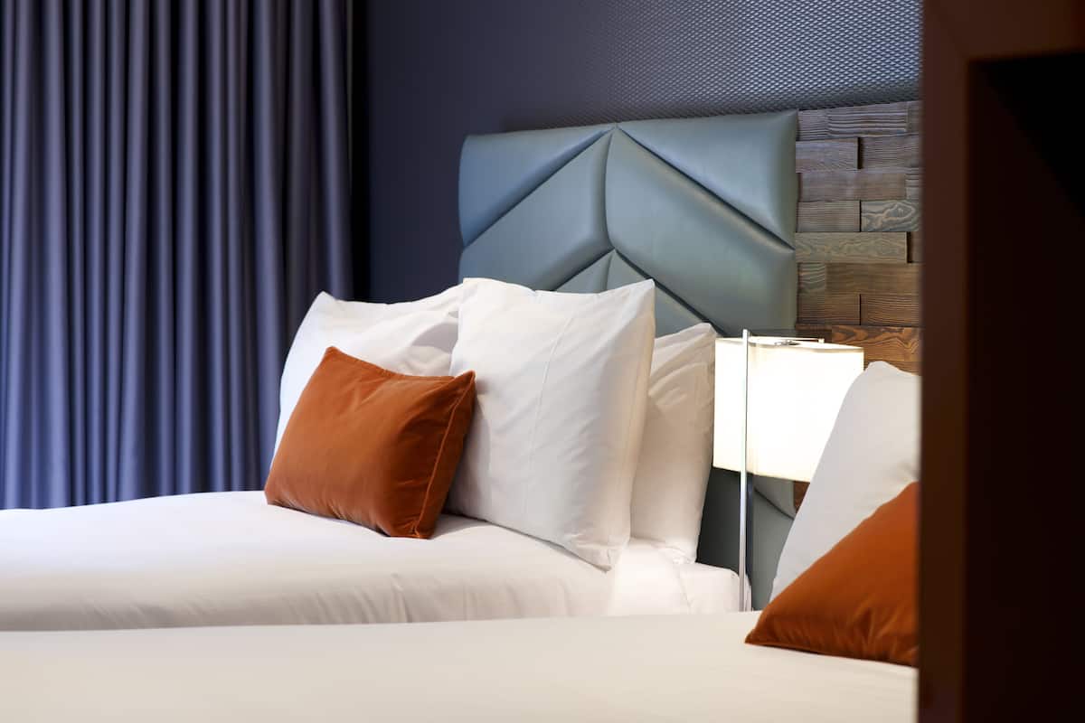 A hotel room with a bed, pillows, and a headboard.
