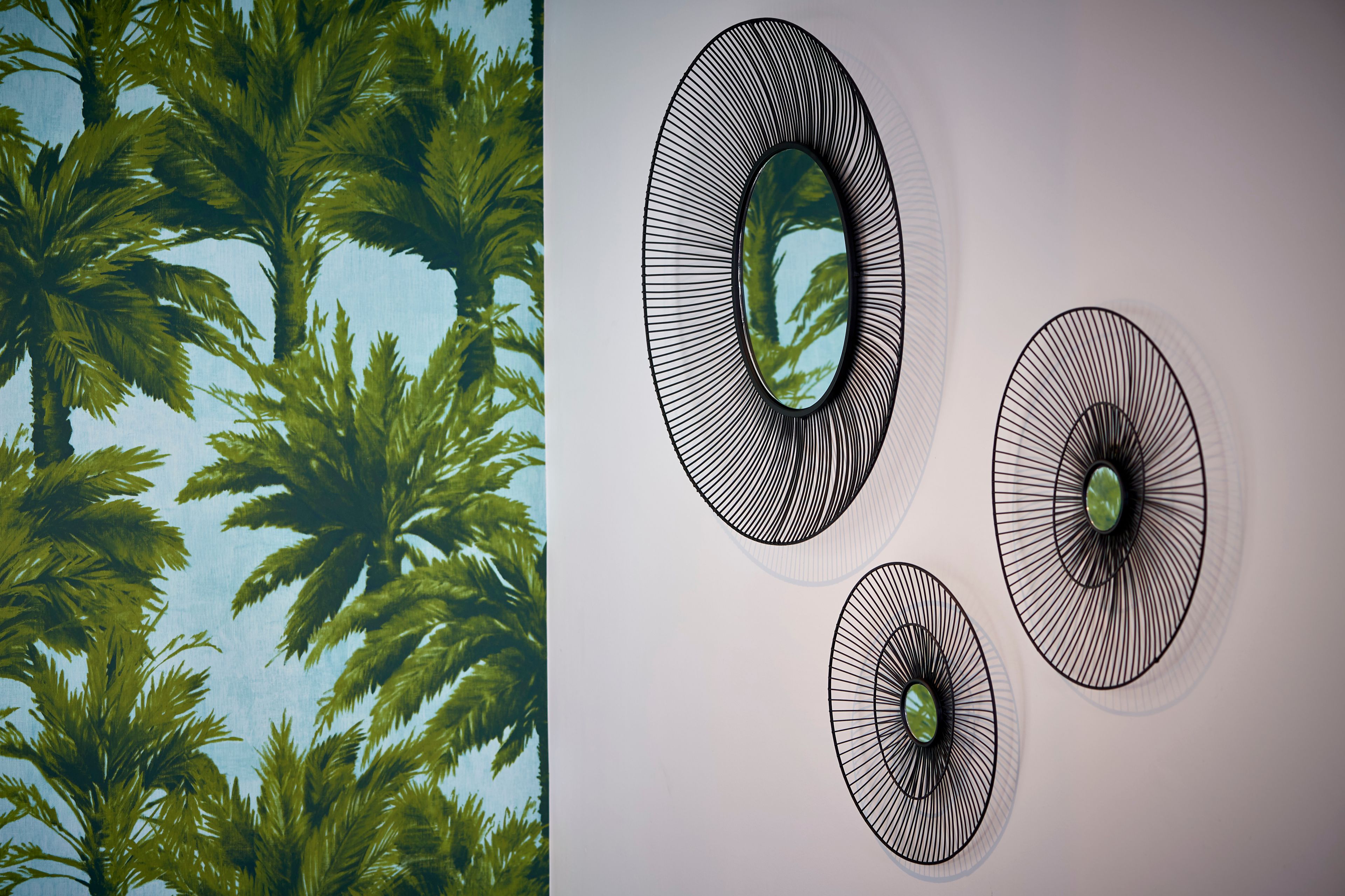 A room with a large window overlooking palm trees, three wall-mounted light fixtures, and a plain wall.