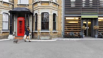 A corner building with a red telephone booth, a black awning, and a modern building with a sign for The Lodge Hotel.