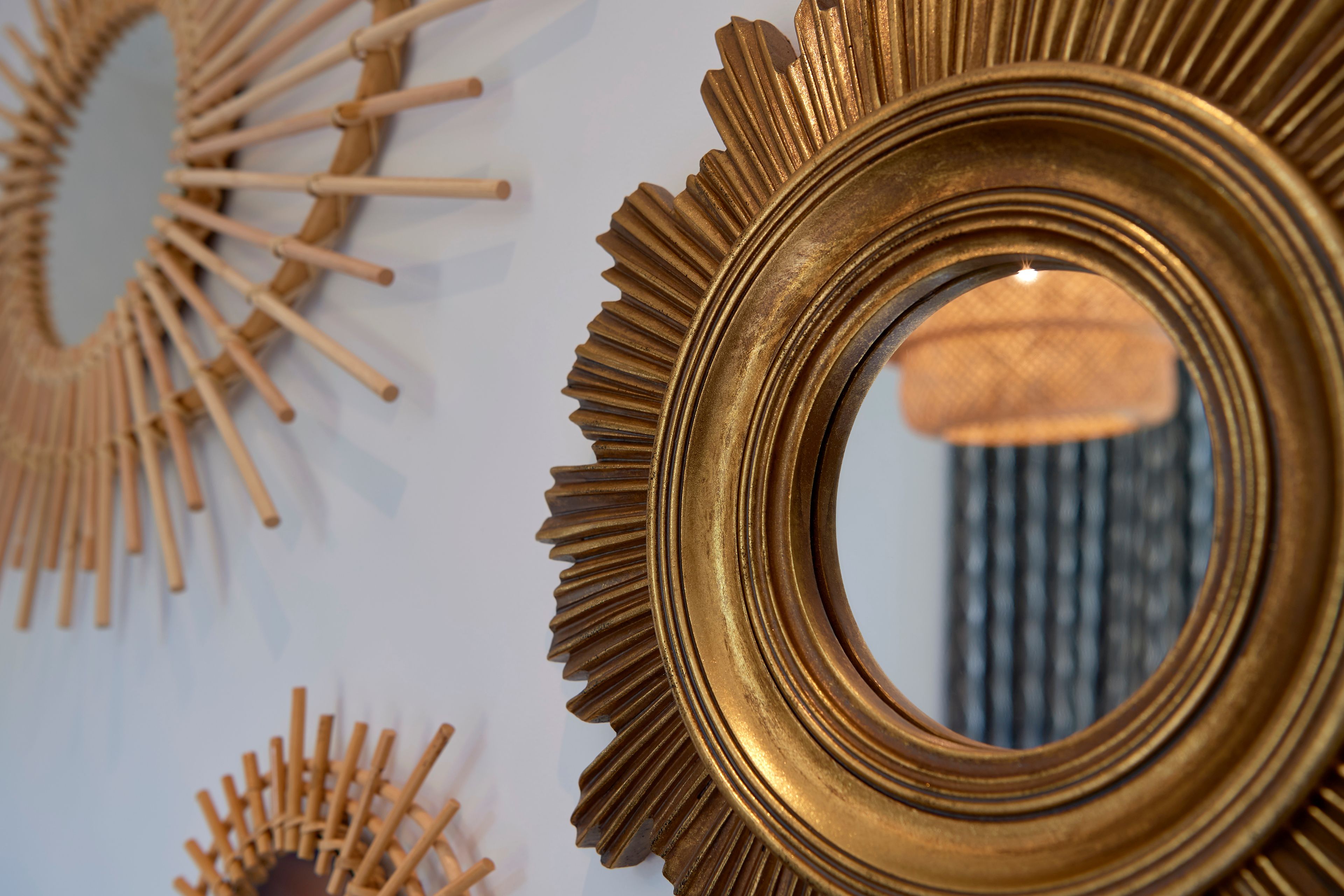A close-up of a wall with decorative golden circular mirrors and wooden elements.