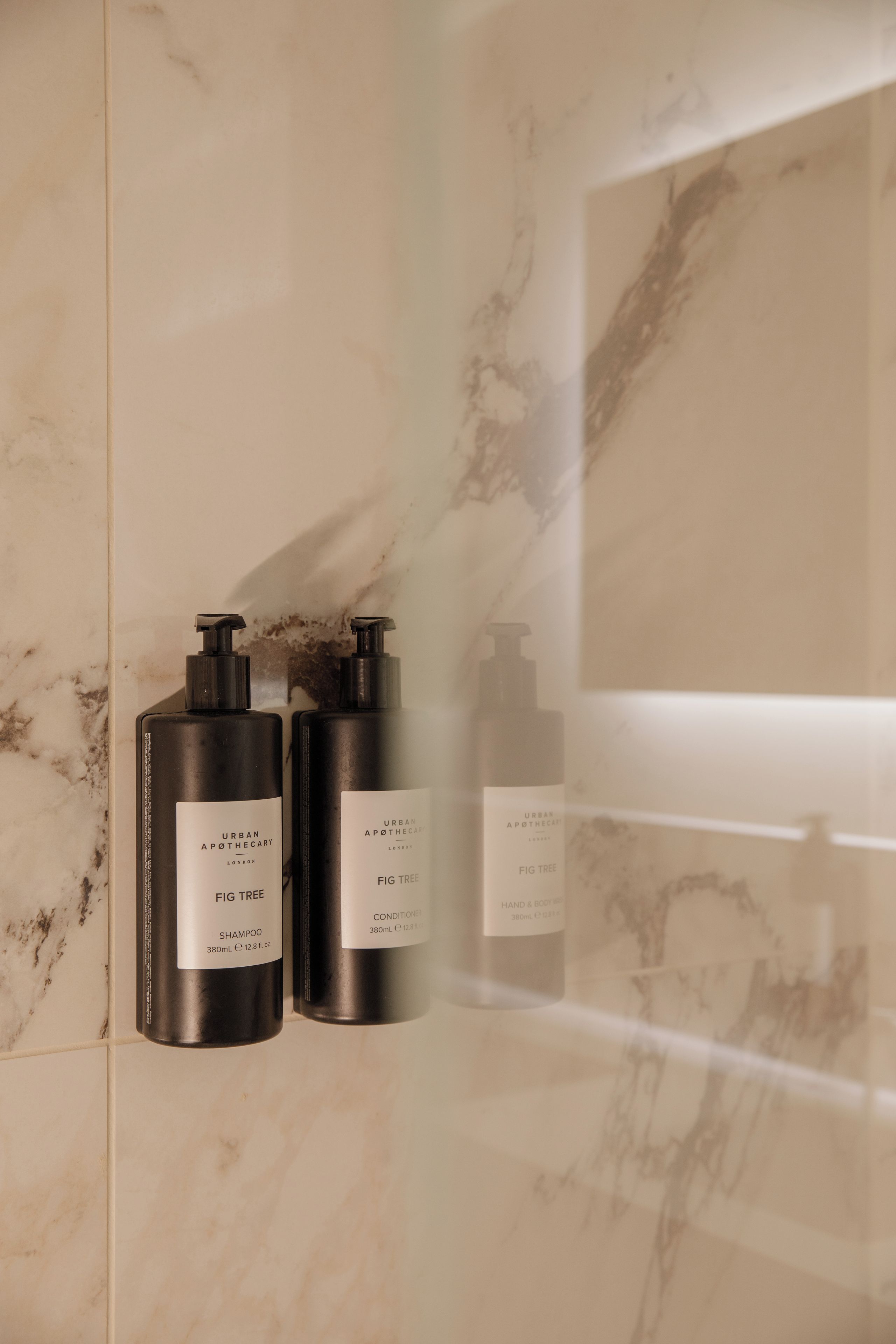Two black bottles of Urban Apothecary products on a marble wall.