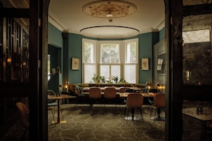 A dining area with a bay window, a sofa, and a table set for dining. - The Lodge Hotel - Putney (London)
