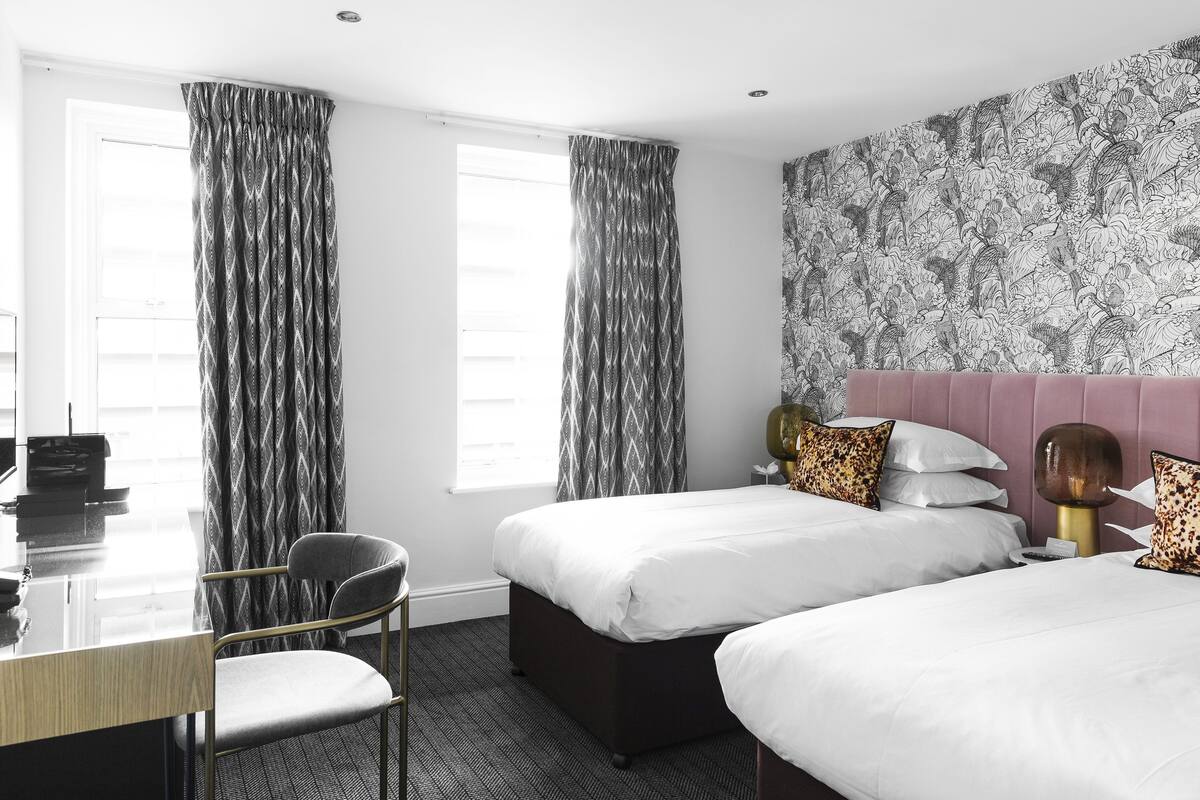 A hotel room with two beds, a desk, and a chair.