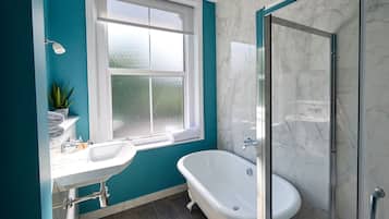 Un baño moderno con una bañera independiente, ducha con cerramiento de vidrio, lavamanos blanco y ventana con vidrio esmerilado.