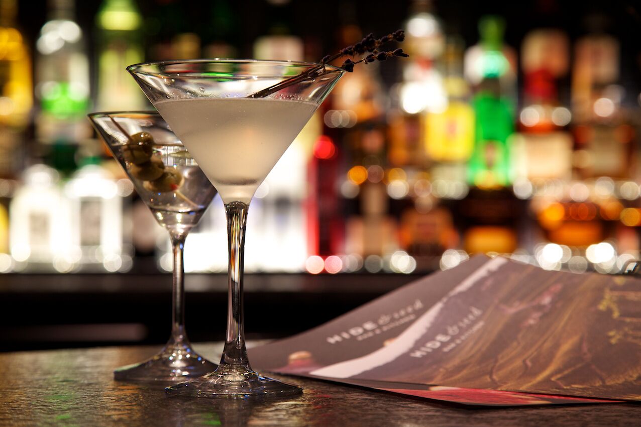 A bar setting with a martini glass and a menu.