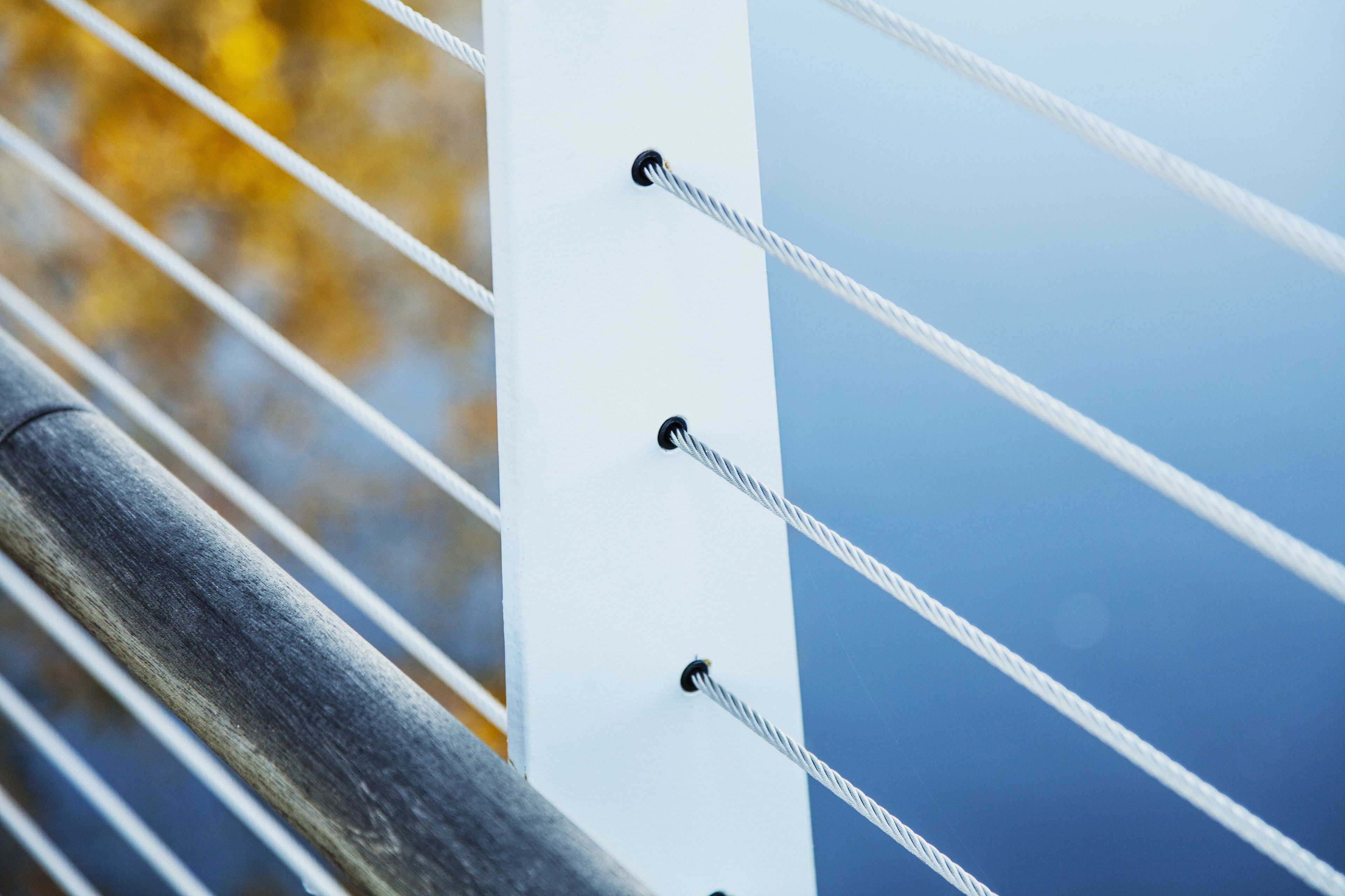 A close-up of a metal railing with cables and bolts.