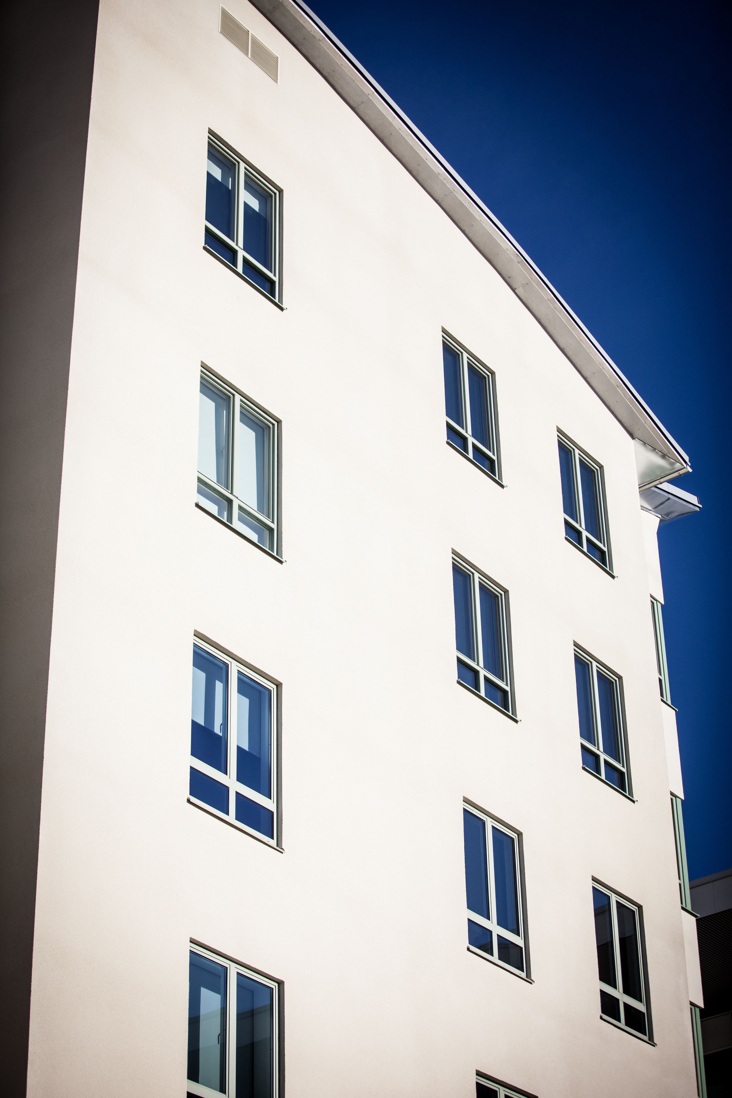 Un edificio de varios pisos con fachada blanca y numerosas ventanas.