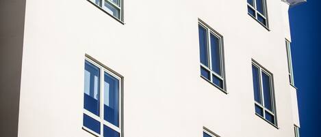 Un edificio de varios pisos con fachada blanca y numerosas ventanas.