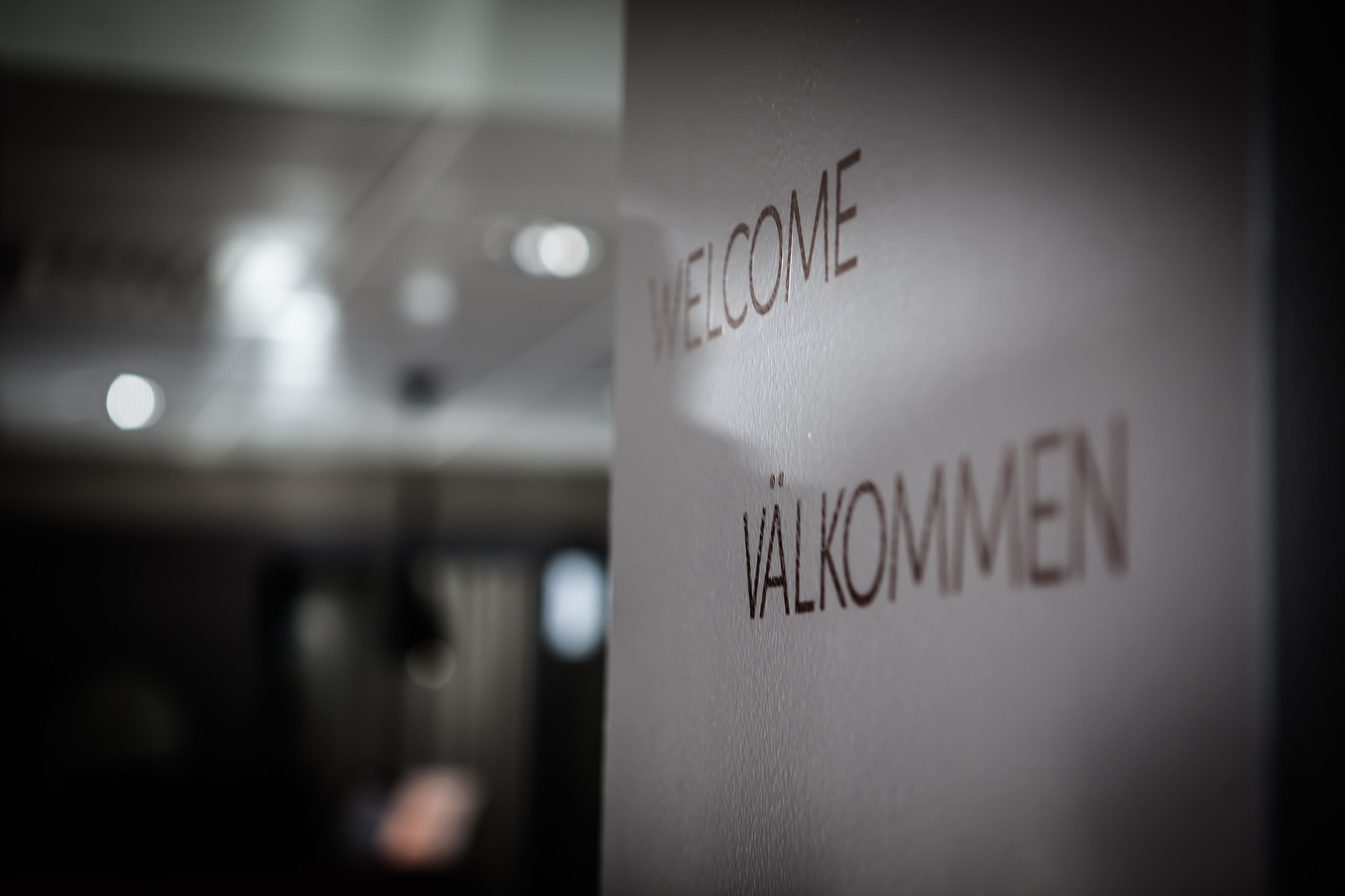 A close-up of a wall with the words "WELCOME" and "VÄLKOMMEN" indicating a multilingual greeting.