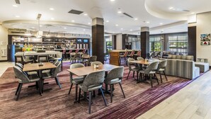A modern hotel lobby with a bar area, seating arrangements, and a large window providing natural light. - Courtyard by Marriott Boston Waltham (Waltham)