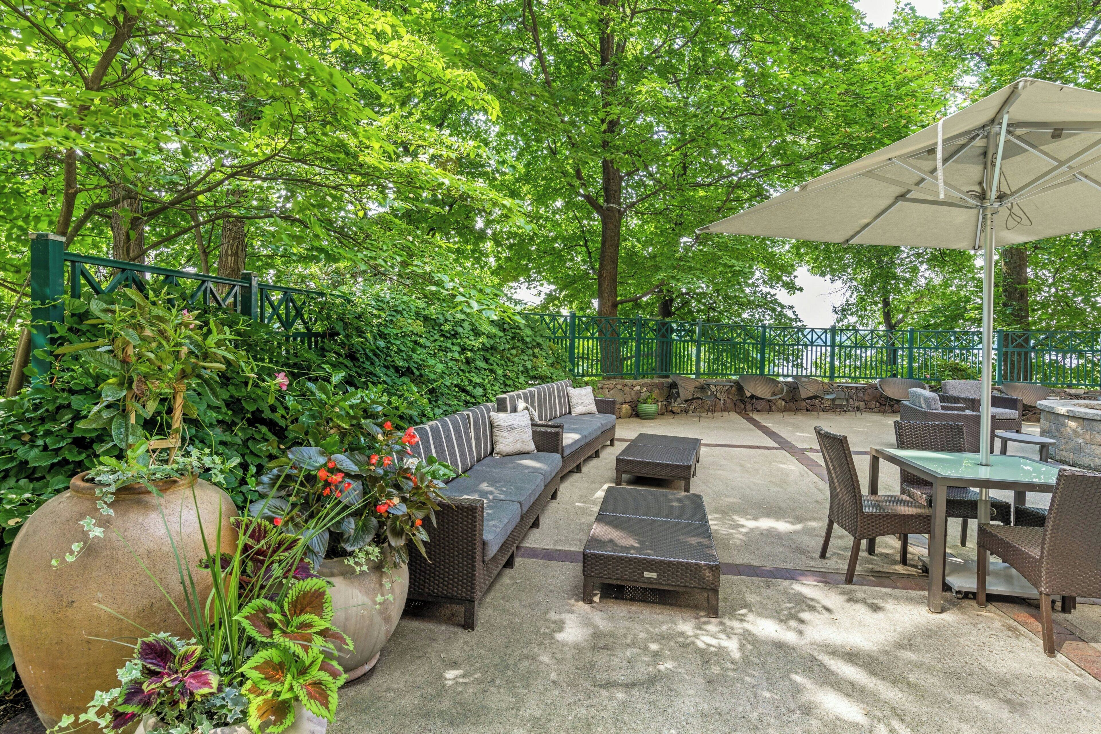 An outdoor patio with a sofa set, dining table, chairs, and a large umbrella.