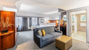 A hotel room with a bed, a sofa, a desk, and a bathroom. - Courtyard by Marriott Boston Waltham (Waltham)