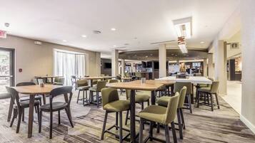 A hotel lobby with multiple seating areas, a reception desk, and a visible Starbucks outlet.