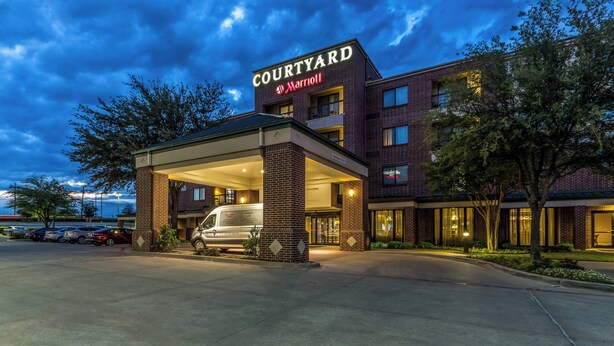 Un hotel Courtyard Marriott con ingresso coperto, facciata in mattoni e un furgone parcheggiato all'esterno.